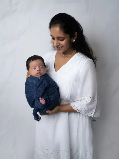 A mother gazes lovingly at her sleeping baby, held close to her heart. This is a simple, elegant portrait that focuses entirely on their special connection.