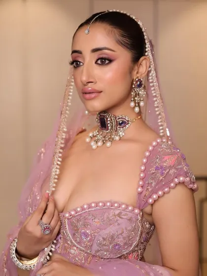 A dazzling glam look perfect for a Sangeet or Reception. This bride's look features dramatic, shimmering eyes, glowing skin, and a sleek hairstyle, all complementing her modern, embellished lavender outfit.