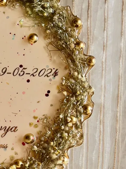 A close-up of an elegant flower photo frame, showing the intricate details of the preserved flowers and golden beads. It's a perfect way to keep memories alive.