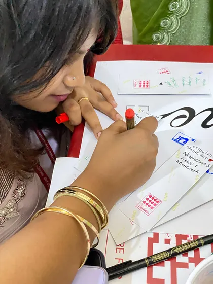 A student adding a personal touch by writing a message on her photo strip envelope.