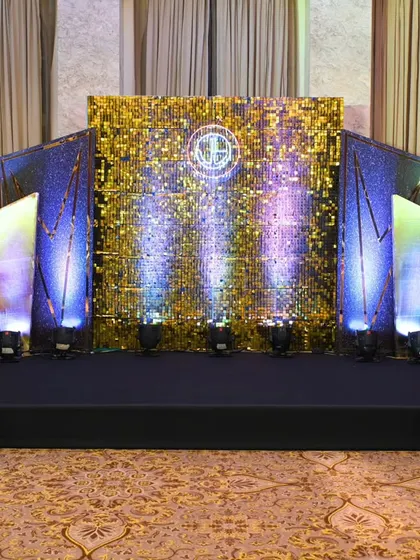 The main stage was the focal point of the event, featuring a gold sequin wall with a custom logo, flanked by art deco panels and dramatic lighting to create a dazzling effect.