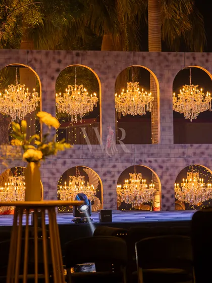 A closer view of the sangeet stage, showing the wall of chandeliers set within arched, mirrored niches. The design creates an infinite reflection of light, making for a truly dazzling backdrop.