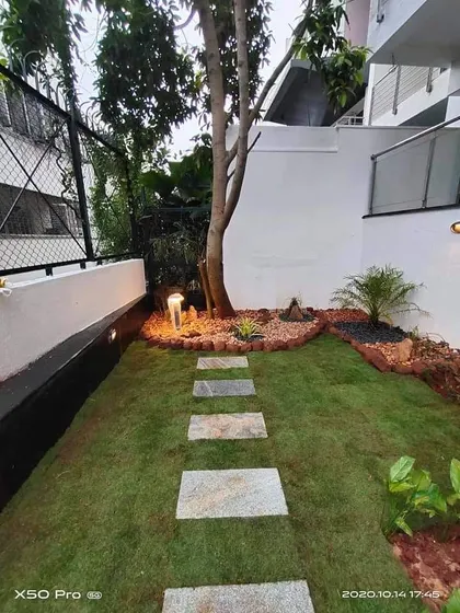 A compact backyard garden featuring a well-lit lawn, a stone stepper path, and a mature tree as a focal point. My lighting designs extend the usability of the garden into the evening hours.