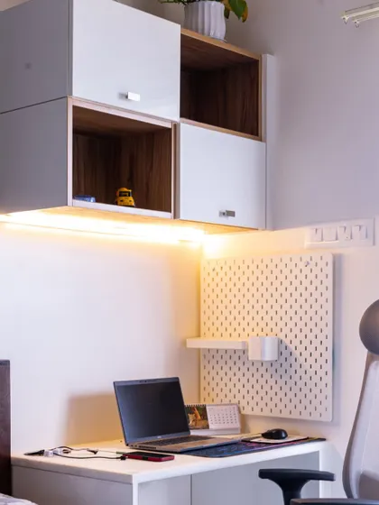 A compact and efficient work-from-home setup within a bedroom. This design includes overhead storage, a pegboard for organization, and under-cabinet lighting for a productive workspace.