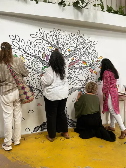 A group of participants adding their personal touch to a collective tree mural. This is what community art is all about.
