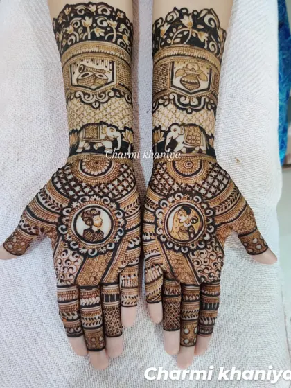 A lovely bridal design featuring custom portraits of the couple within ornate circular frames. The arms include traditional elements like a doli (palanquin) and elephants, symbolizing the wedding journey.
