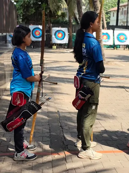 Two young girls waiting on the shooting line. They learn from and support each other.