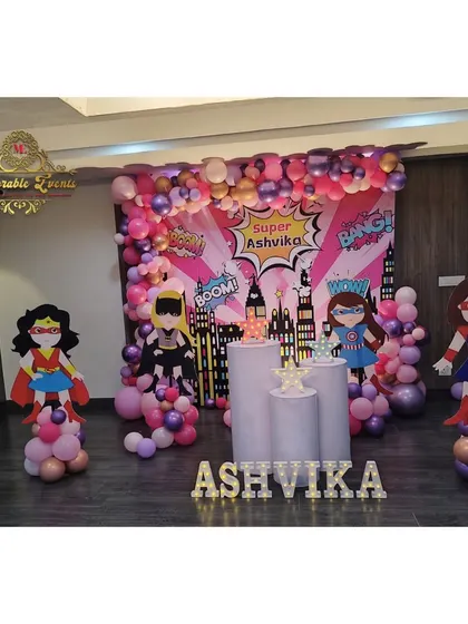 A super-girl themed party with a city skyline backdrop and cutouts of female superheroes like Wonder Woman. The pink and purple color scheme adds a unique touch.