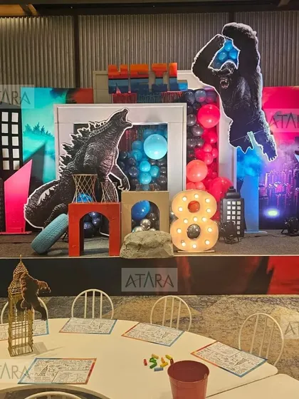 A monstrously fun Godzilla vs. King Kong themed party. The stage is set with city skyline cutouts and epic figures of the two titans, creating a battle scene for an 8th birthday celebration.