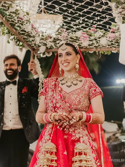 The bride's happy entrance under a 'phoolon ki chadar', her smile lighting up the frame.