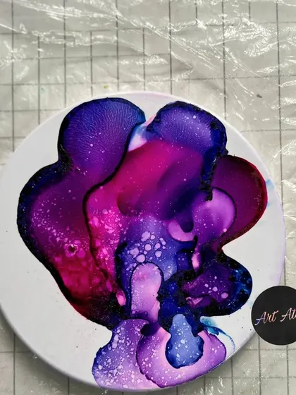 A coaster created using the fire technique with alcohol inks, resulting in a beautiful, galaxy-like pattern.