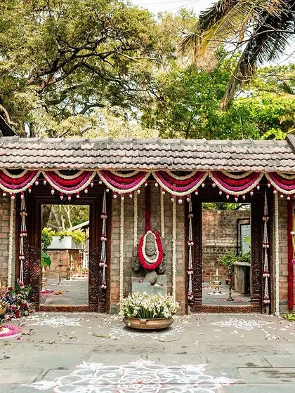The entrance to a wedding venue, beautifully decorated in a traditional South Indian style with brick, wood, and marigold flowers.