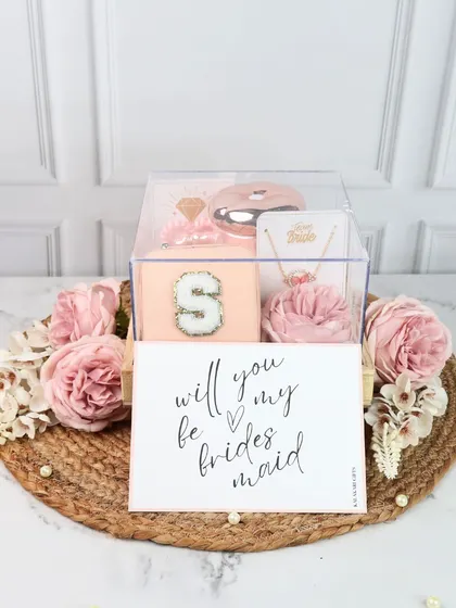 A simple yet elegant bridesmaid proposal gift. This clear acrylic box contains a personalized jewelry case, a custom necklace, and a "Will you be my bridesmaid?" card, all beautifully presented on a bed of jute.