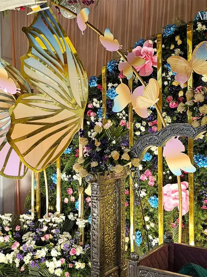 A close-up of the iridescent butterfly wings and the floral backdrop. The mix of fresh flowers and custom props creates a truly unique and memorable setting.