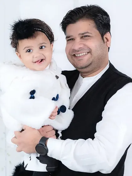 A happy father holds his daughter, who is sticking her tongue out playfully. A real and fun moment captured perfectly.