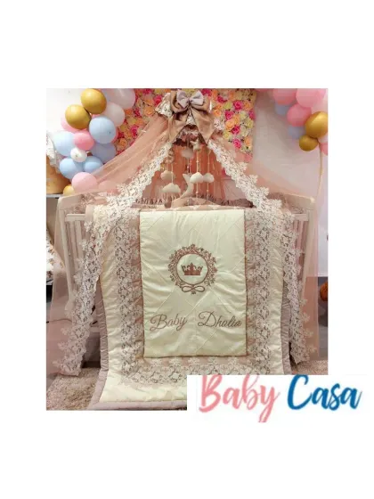 The full view of a magnificent royal nursery. This setup includes a personalized quilt, pillow bumpers, and a stunning lace-trimmed canopy, all tied together with a soft, elegant color scheme.