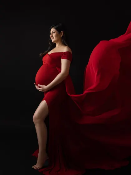 For moms who want a bold and dramatic statement, I use vibrant gowns from my studio wardrobe and techniques like fabric tossing to create powerful, dynamic maternity portraits against a classic black backdrop.