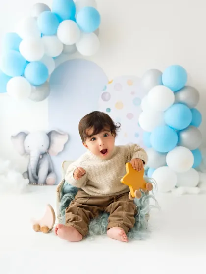 A baby boy makes a surprised and happy face during his first birthday celebration shoot. Capturing these expressions is what makes baby photography so fun.