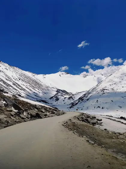 Driving through a path carved out of snow. An unforgettable part of our early-season Ladakh bike trips.