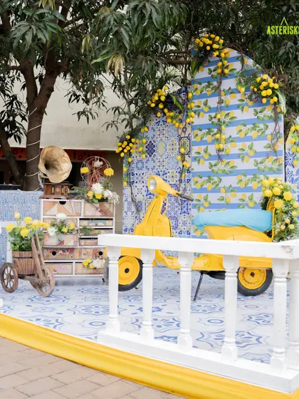 A picturesque photo corner at a Haldi ceremony. The vintage yellow scooter set against a blue-and-white tiled backdrop with lemon accents created a perfect Instagrammable spot.