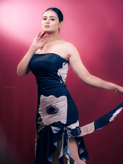 A three-quarter portrait with a focus on the model's pose and the texture of the dress. The pink background adds a vibrant, modern feel.