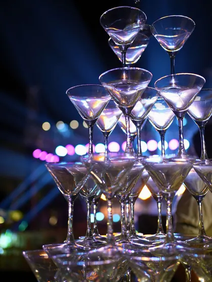 A champagne tower ready for a grand toast, set against the vibrant lights of the Sangeet stage.