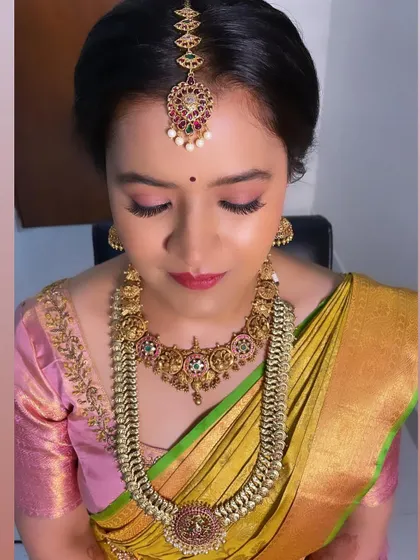 A classic bridal makeup look. The pink eyeshadow and bold lip are perfect for a wedding ceremony, paired with heavy gold jewelry.