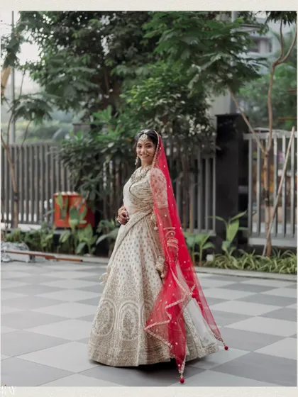 A full-length shot of the bride looking back with a smile, her red veil adding a vibrant pop of color.