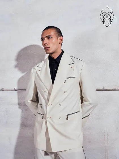 A full look of the Ivory Industrial suit. The double-breasted silhouette is given a contemporary update with sharp contrast piping and bold hardware, creating a look of polished presence.