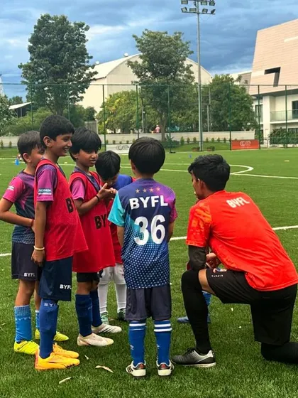 A coach kneels to give tactical instructions to a small group of young players. These huddles are essential for building team chemistry and ensuring every child understands the goal of the drill.