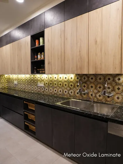 The dual-tone cabinetry in this kitchen pairs a natural wood finish on top with a dark, textured laminate below. Under-cabinet lighting highlights the unique backsplash.