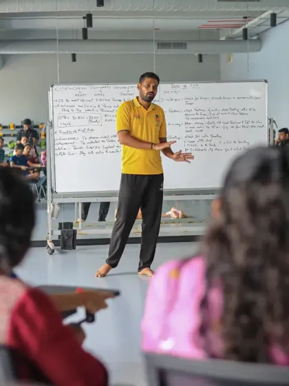An instructor leads a classroom session during the CPR workshop, explaining the theory behind emergency response using a whiteboard.