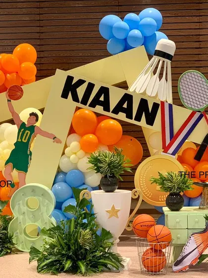This dynamic sports-themed backdrop features abstract panels, a giant shuttlecock, and tennis rackets, creating an action-packed setting for a young athlete's birthday.