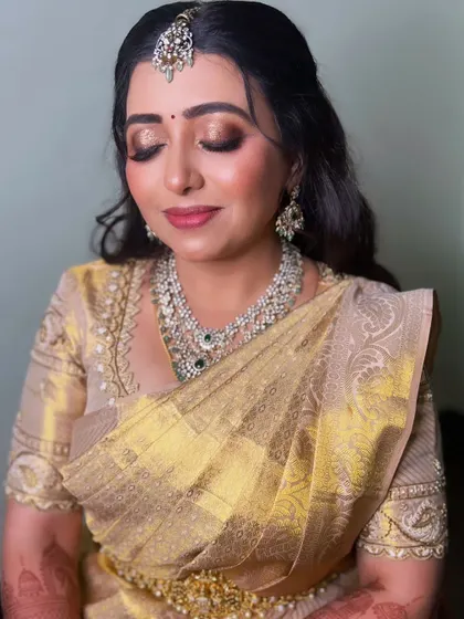 For her reception, this Iyengar bride switched to a glamorous look with a golden silk saree and sparkling diamond jewelry. The makeup features a bronze smokey eye and a glossy nude lip.