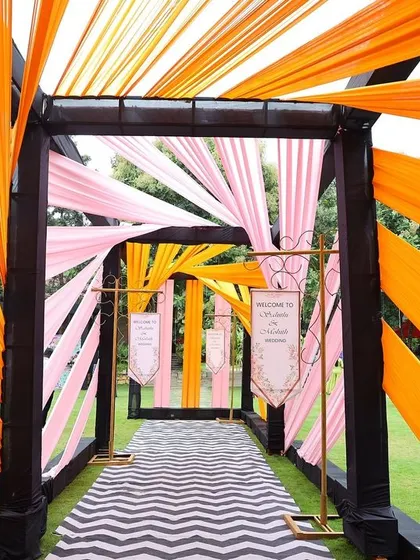 A dynamic entrance pathway for a carnival-themed event, with bright orange drapes creating a tunnel of color.