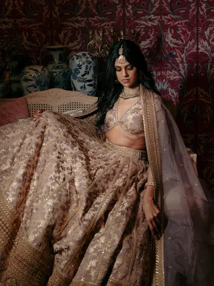 A luxurious portrait of the bride, Bandhavi, seated, the rich texture and detail of her Sabyasachi lehenga filling the frame.