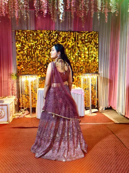 A back view of the client in the shimmery purple lehenga, showing off her look against the festive decor.