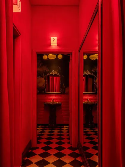 A corridor at BANNG leading to the washrooms, where the immersive red theme continues. The space plays with reflections and theatricality, using mirrors and curtains to create a sense of discovery even in transitional areas.