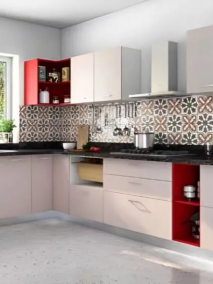 This L-shaped kitchen combines off-white cabinets with pops of red in the open shelving. The patterned backsplash adds a traditional Indian touch to the modern design.