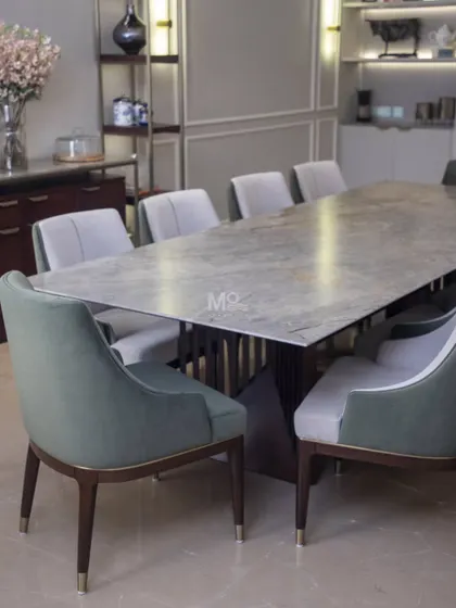 The Aurum Dining Set, featured in a Delhi NCR residence, is a statement of contemporary grace. The solid wood table with soft edges is complemented by ergonomically designed chairs in a luxurious dual-tone fabric finish, creating an inviting dining experience.