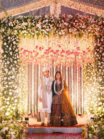 A full view of the couple at their varmala under a stunning floral hanger. This was our Plan B due to monsoon rains, and it ended up stealing the show.