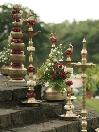 An assortment of traditional brass lamps and pots of different sizes, decorated with flowers, creating a stunning display on the mandap steps.