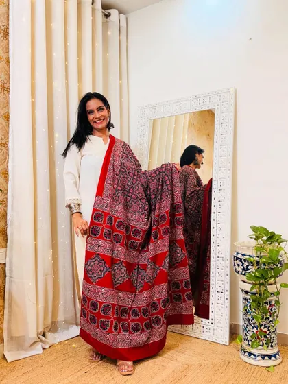 An elegant off-white solid suit paired with a vibrant red and black printed dupatta. This shows how a beautiful dupatta can instantly elevate a simple outfit.