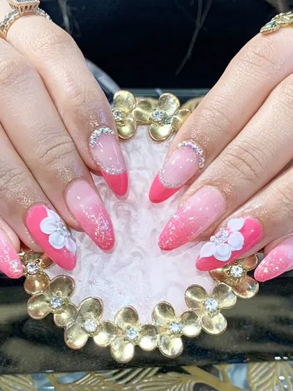 A fun and feminine design with a pink ombre base, white 3D flowers, and a French tip style.