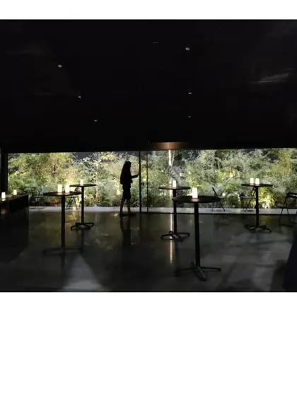 The interior of the Durall Pavilion, where a horizontal window frames a lush garden. The all black space becomes a quiet backdrop, allowing the view and the people within it to become the focus.