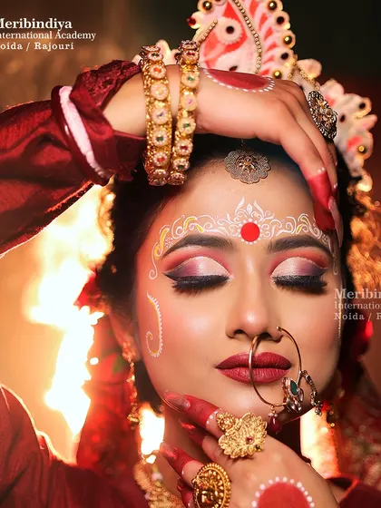 A classic Bengali bridal look, featuring a traditional bun adorned with a 'sholar mukut' and intricate white 'chandan' designs on the forehead.