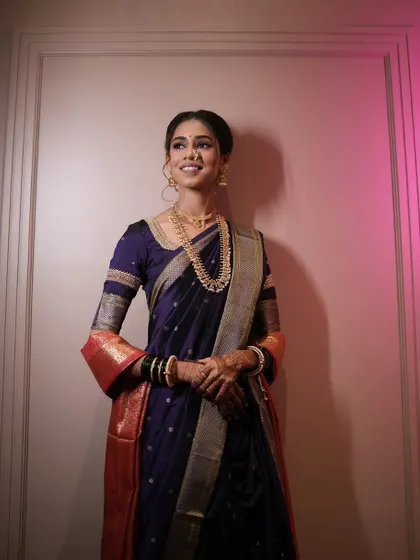 A full-length portrait of the bride in her elegant purple Nauvari saree.