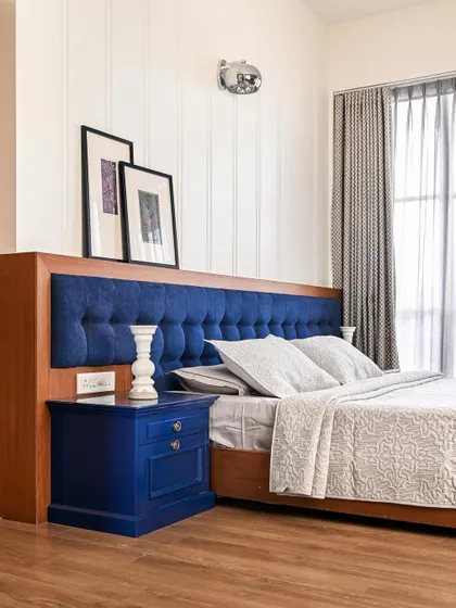 A close-up of the master bedroom's tufted blue headboard and matching custom-painted side table.