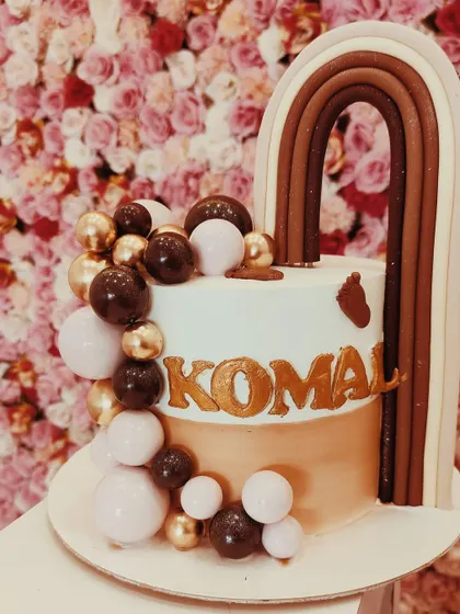 A stylish and modern cake with a brown-toned rainbow and a cascade of chocolate-colored spheres. It's a chic design for an adult's birthday.