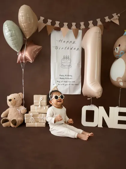 A full-width shot showcasing the entire brown and neutral-toned birthday setup, with the cool little guy posing in the center.